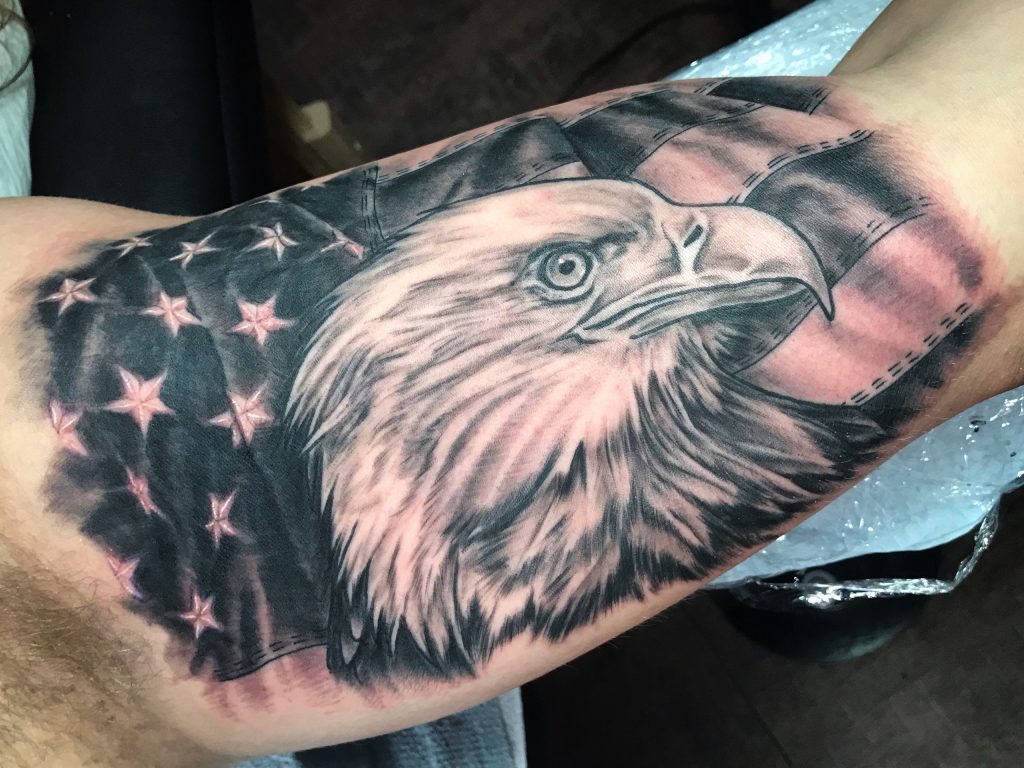 Bald eagle and stars-and-stripes tattoo on the forearm.