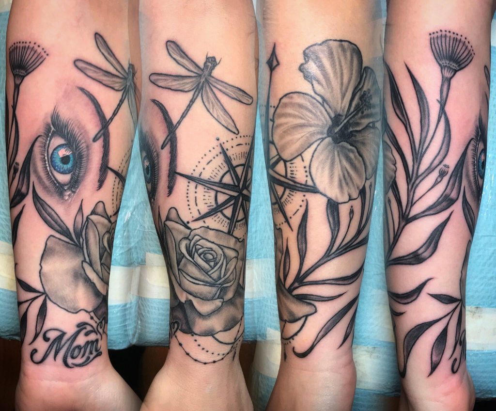 Botanical leg tattoos with flowers, dragonflies, and an eye.