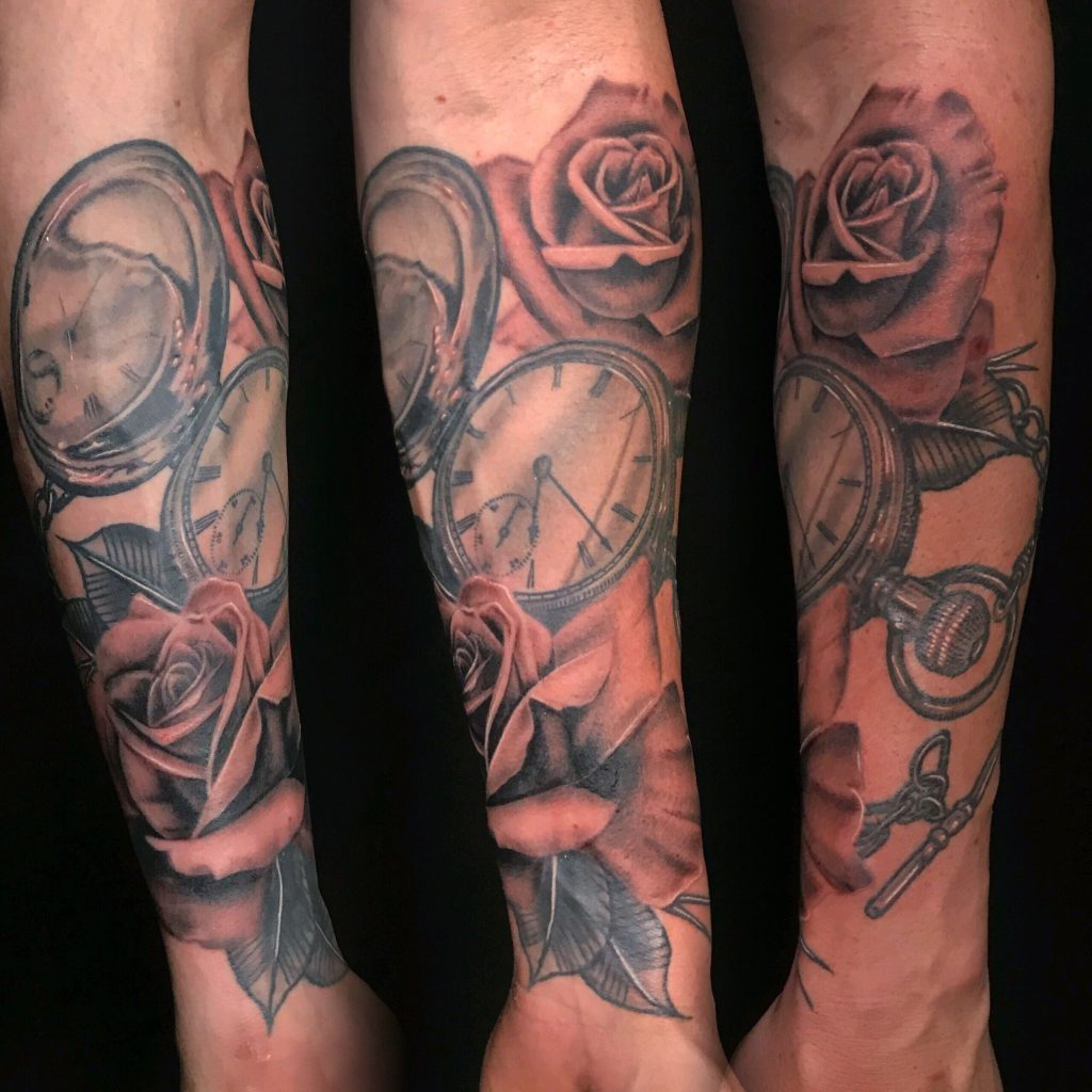 Black-and-grey roses and clock faces tattooed on the lower legs.