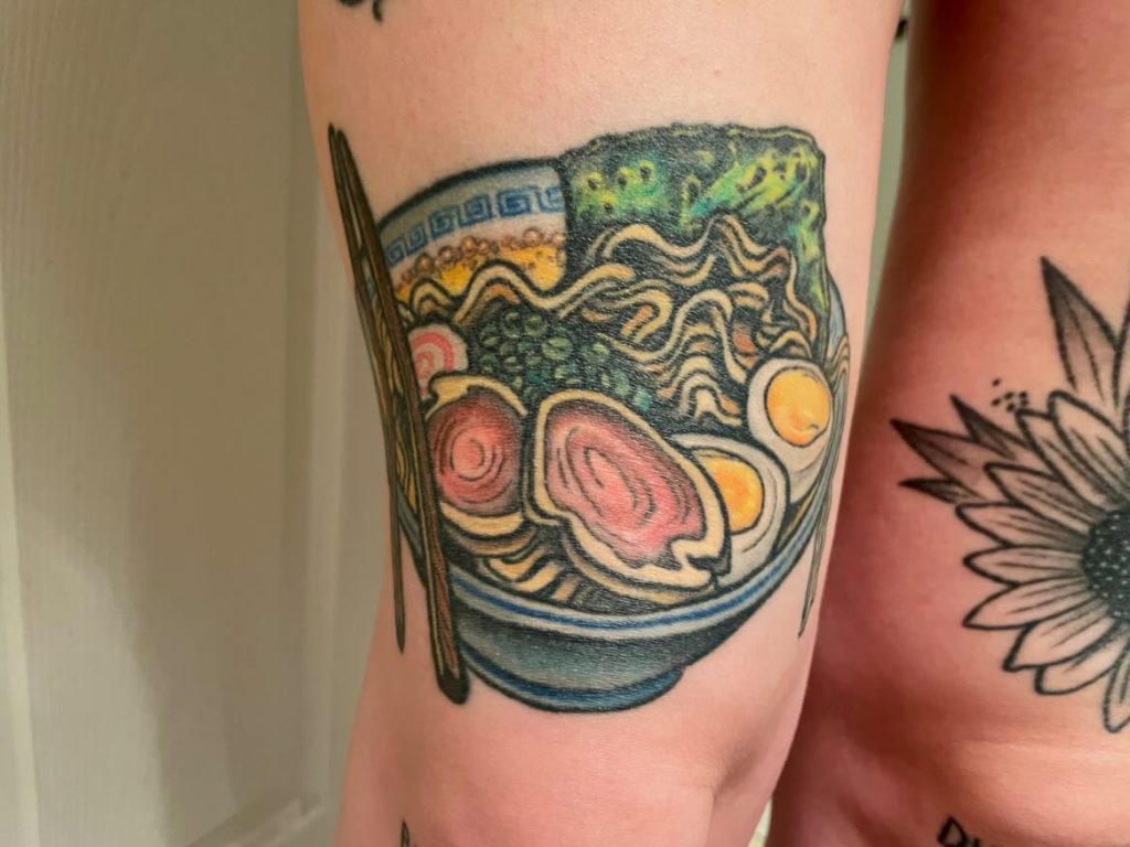 Colorful abstract tattoo with waves and circular shapes on the thigh.