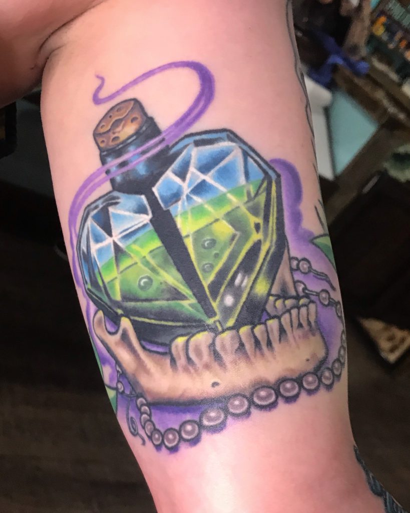 Blue-green gemstone surrounded by purple tentacles on the upper arm.