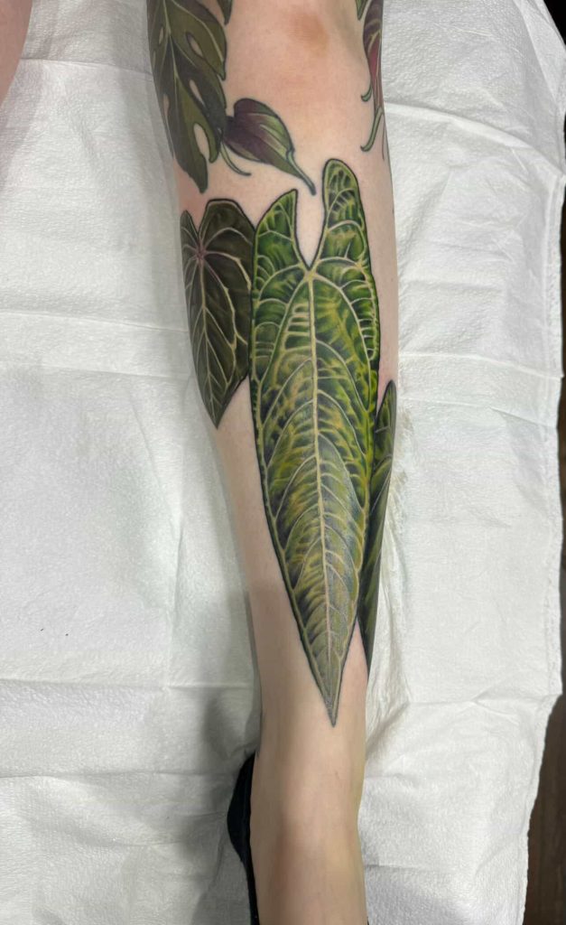 Large green leaf tattoo covering the lower leg.