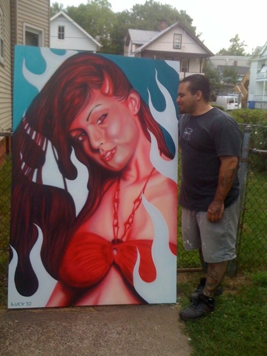 Outdoor painting of a red-haired figure in red clothing against blue.